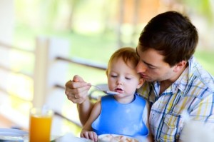 Jeune papa nourrissant son bébé.