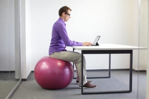 une homme travaille sur ordinateur assis sur une boule