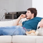 Un homme regarde la télévision en mangeant
